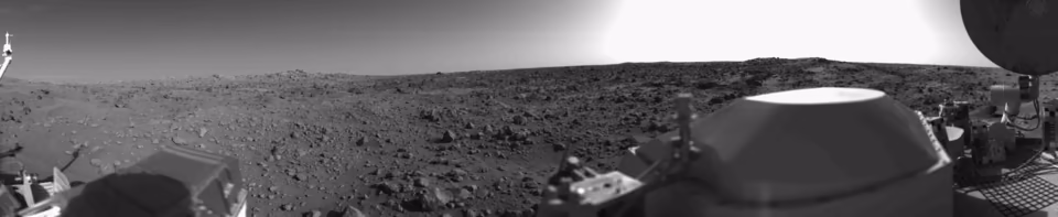 Das Panorama der Marsoberfläche von Viking I: eine flache, mit Steinen übersäte Ebene bis zum Horizont, im Vordergrund Teile des Landers.